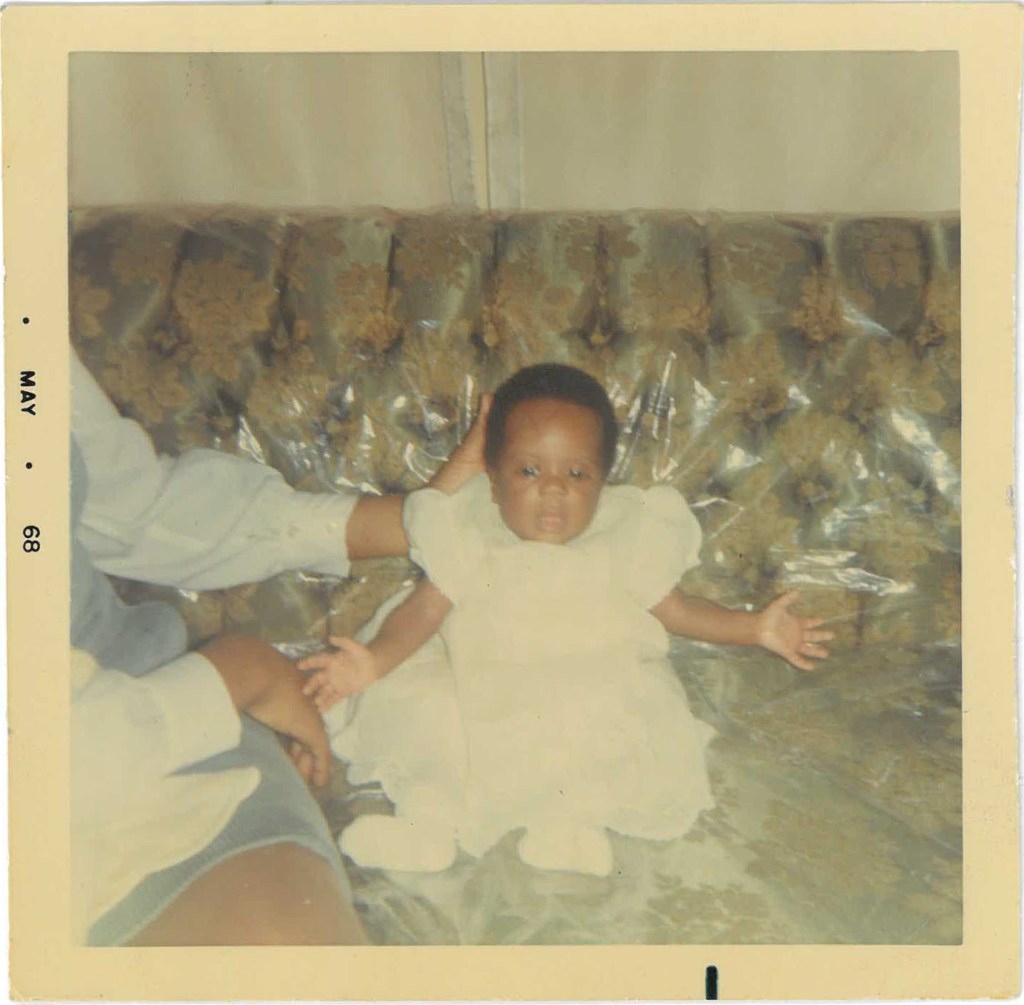 Faded, square photograph of Baby Shari on the family couch, 1968.