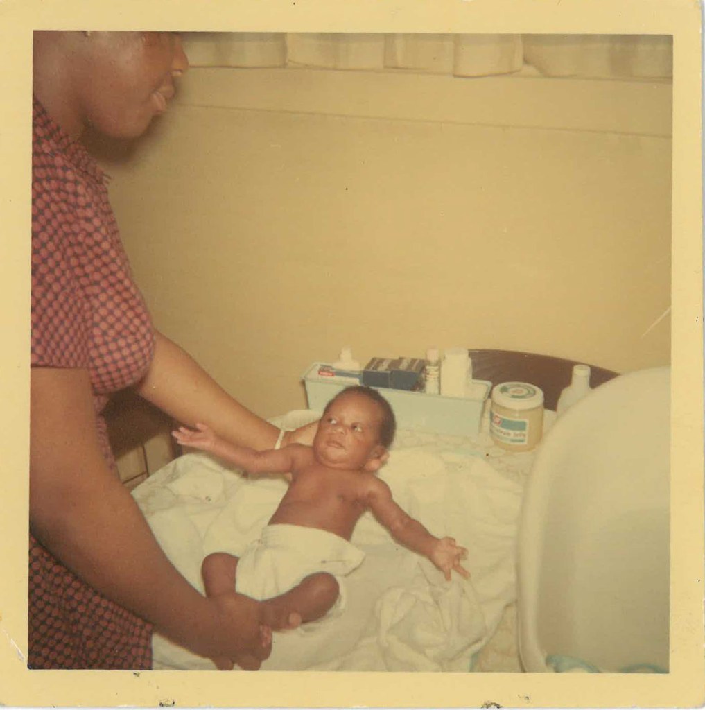 Faded, sepia-toned photo of Baby Shari and her mother during a diaper change.